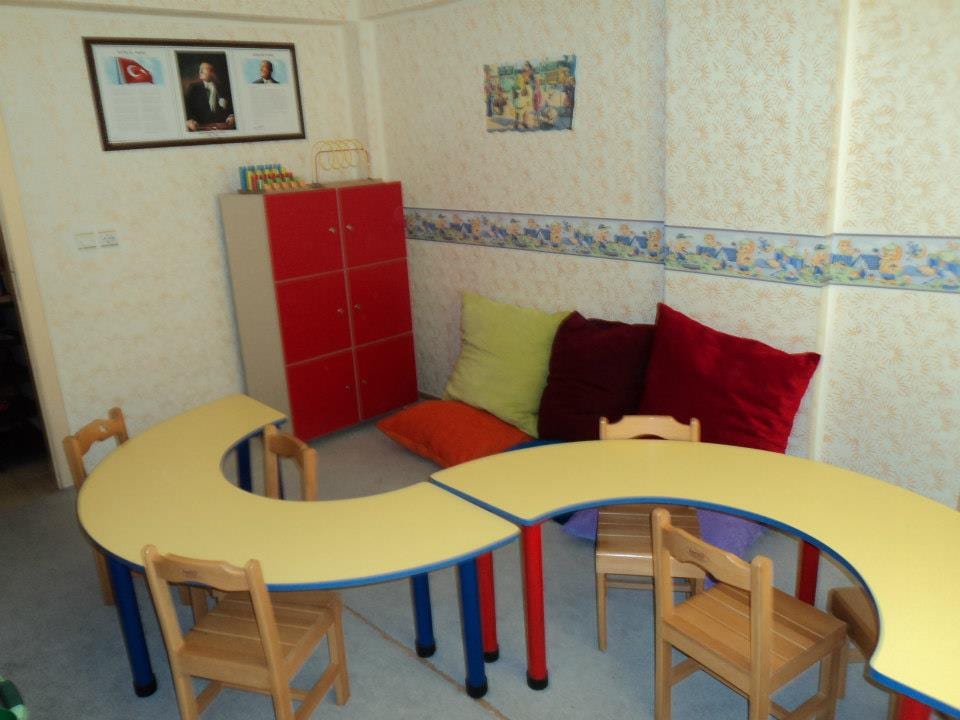 Grup eğitim odası: dalga biçimli ortak masa, renkli dolaplar ve oturma köşesi